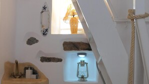 Un baño pequeño con un lavabo de madera, un farol y una ventana con vistas al exterior.