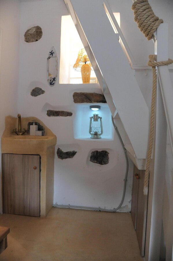 Un baño pequeño con un lavabo de madera, un farol y una ventana con vistas al exterior.