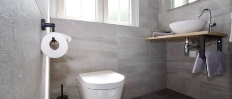 Une salle de bain moderne équipée de toilettes, d’un lavabo et d’un miroir.