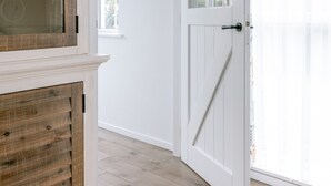 Un pasillo con un armario de madera, una puerta blanca y una ventana.
