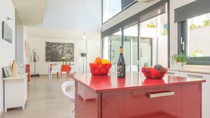 A modern kitchen with a red island, a dining area with a white table and red chairs, and a cityscape artwork on the wall. - MARTE - Chalet with terrace in Sa Pobla. Free WiFi (Sa Pobla)