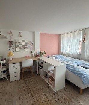 Une chambre à coucher comprenant un lit, un bureau, une chaise et des meubles de rangement.