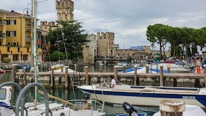 A marina with boats docked, a historic tower, and a bridge in the background. - Bed & Breakfast Le Reve (Sirmione)