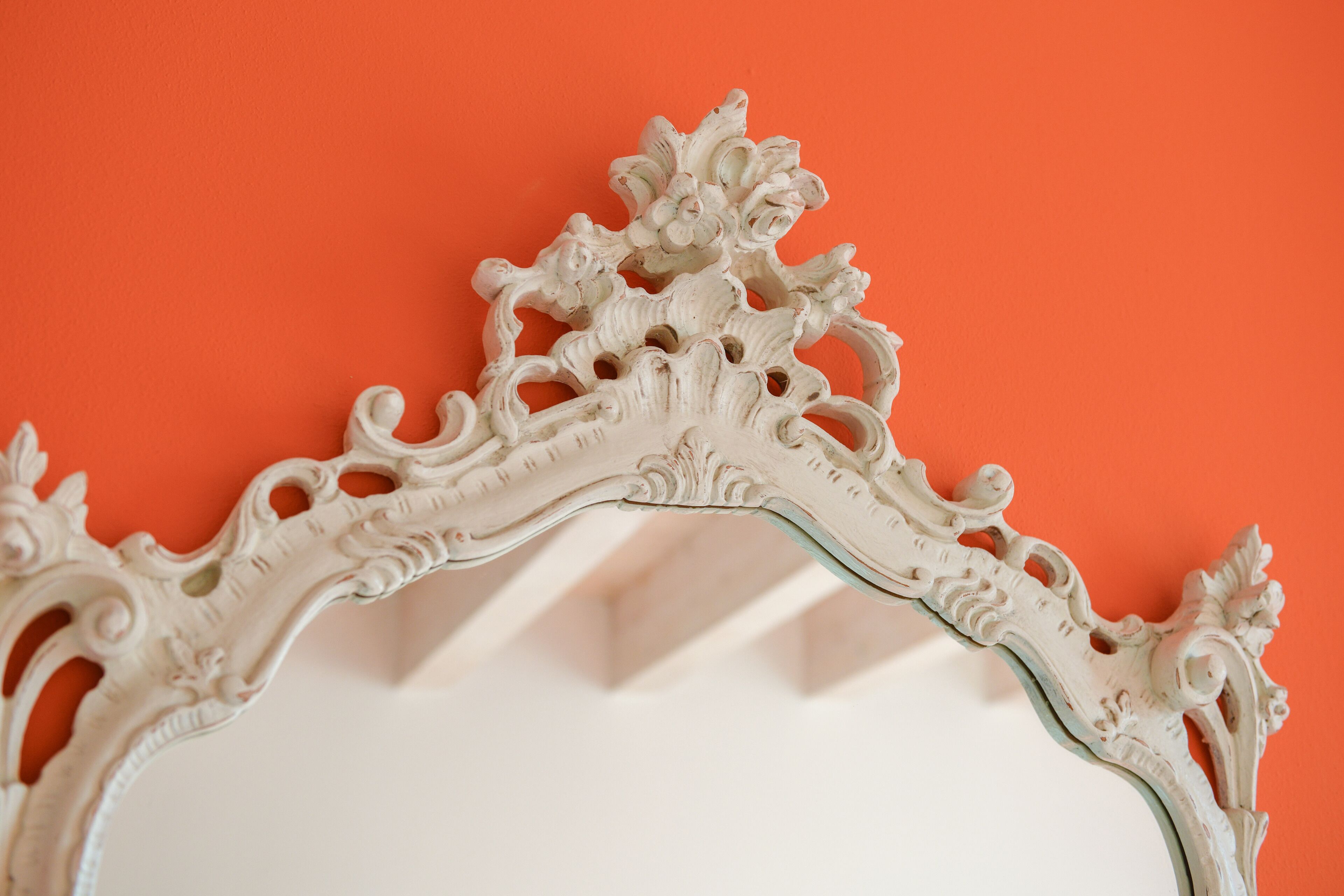 Un miroir décoratif aux motifs complexes, sur fond orange.