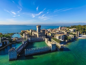 A coastal town with a historic castle surrounded by water, featuring a fortified wall and a tower. - Bed & Breakfast Le Reve (Sirmione)