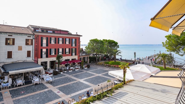 A courtyard with outdoor seating, a restaurant, and a view of the sea. - Bed & Breakfast Le Reve (Sirmione)