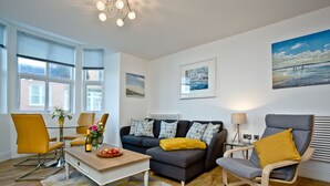 A modern living room with a sofa, armchairs, a coffee table, and artwork on the walls. - 5 At The Beach - Beachfront, Parking, Pets welcome (Torcross)
