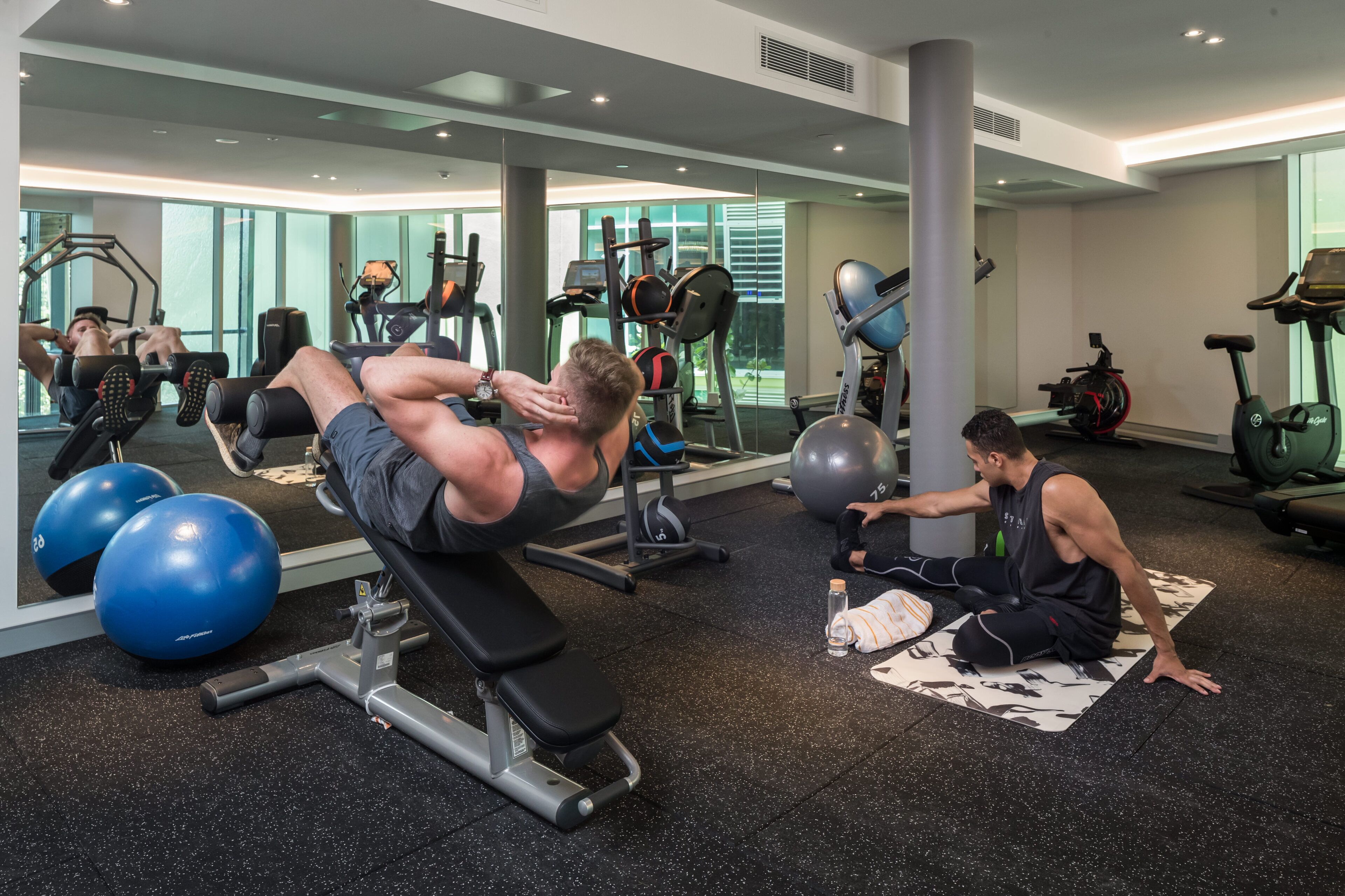 Un gimnasio con equipo de ejercicio, espejos amplios y un diseño espacioso.