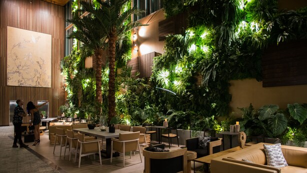 A modern indoor space with a dining area, seating, and a large wall with greenery. - Crystalbrook Bailey (Cairns)