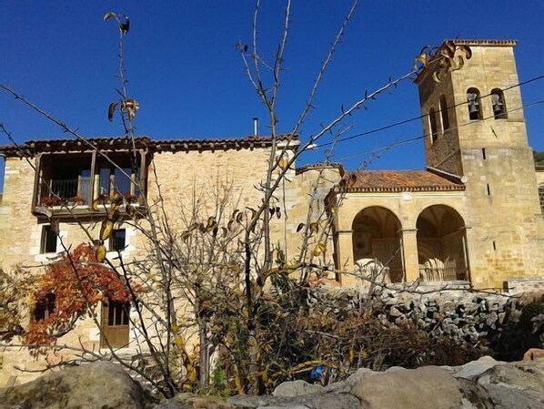 Un edificio de piedra con una torre de campanas, ventanas arqueadas y un balcón.