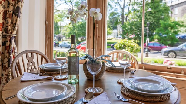 A dining table set with plates, cutlery, and a bottle of Pinot Grigio wine.