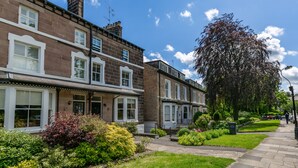 A row of terraced houses with a well-maintained garden and a clear blue sky.