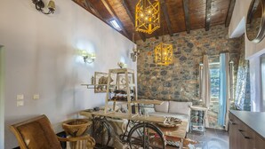 A rustic interior with a stone wall, wooden furniture, and a bicycle. - Dandy Villas Palios Agios Athanasios | Attic | Fireplace | Up to 8 (Agios Athanasios)