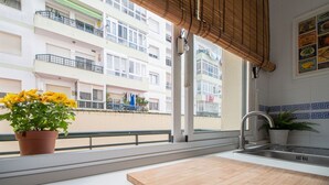 A balcony with a potted plant and a view of a residential building. - Apartamento El rosal de Huertas (Cádiz)