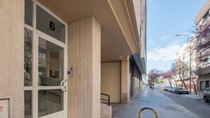 A building entrance with a glass door, a number '6' above it, and a metal handrail on the sidewalk. - Apartamento El rosal de Huertas (Cádiz)