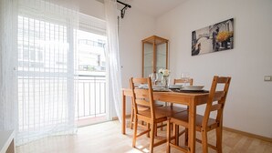A dining area with a wooden table and chairs, a mirror, and a painting on the wall. - Apartamento El rosal de Huertas (Cádiz)