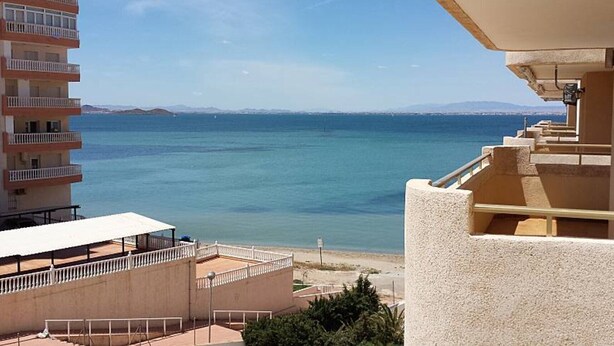 Vista sulla costa con un edificio con balconi affacciati sul mare.
