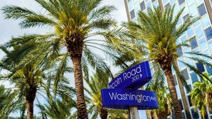 A street sign with 'Lincoln Road' and 'Washington Ave' in front of a modern building with palm trees. - Baybreeze Apartments by Lowkl (Miami Beach)