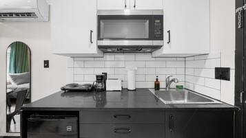A modern kitchen with a microwave, coffee maker, and sink.