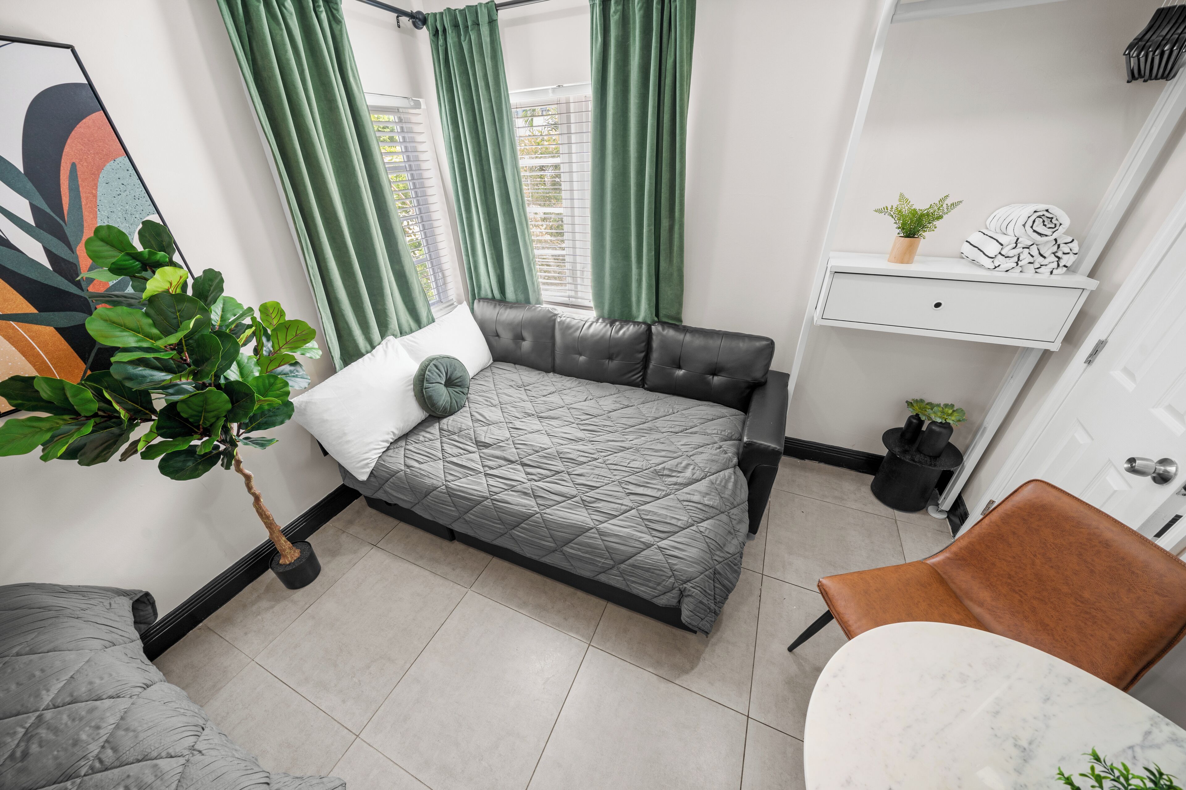Un dormitorio pequeño con cama, un escritorio, una silla y una planta en maceta.