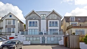 Une maison moderne à deux étages, dotée d’un garage, de grandes fenêtres et d’un balcon.