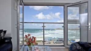 Une pièce dotée d’une grande porte vitrée donnant sur un balcon avec vue sur l’océan et la plage.