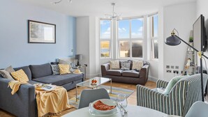 Un salon moderne avec un mur bleu, deux canapés, une table basse et un coin repas.