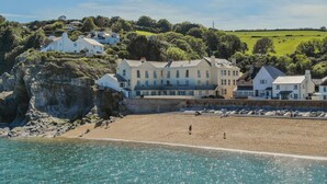 Un bâtiment à plusieurs étages situé sur la côte, sur une falaise surplombant une plage.