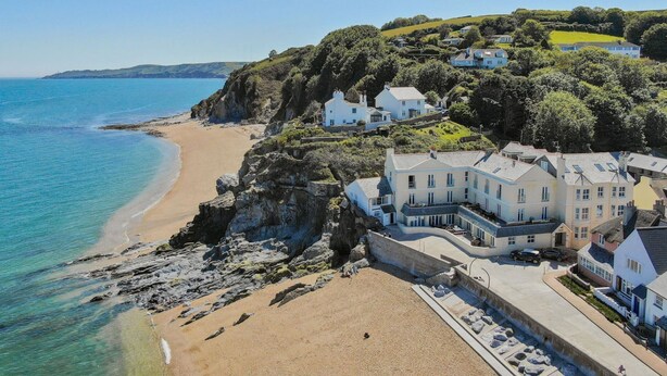 Une propriété située sur la côte, comprenant plusieurs bâtiments, une plage et une falaise surplombant la mer.