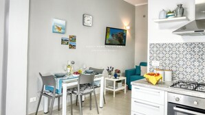 Une cuisine moderne équipée d’une cuisinière à gaz, de meubles blancs et d’un coin repas avec une table et des chaises.