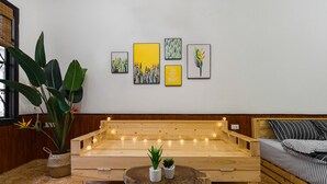 A wooden bench with string lights, a bed with striped bedding, and a wall with framed artwork. - Michi House (Hanoi)