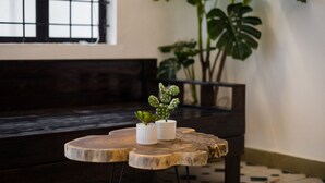 A wooden bench and a round wooden table with two white pots containing plants. - Michi House (Hanoi)
