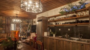 A rustic kitchen with wooden cabinets, a stone wall, and a black tiled backsplash. - Dandy Villas Palios Agios Athanasios |Rustic | Fireplace | Up to 6 (Agios Athanasios)