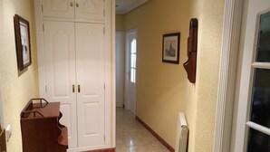 Un pasillo con una puerta doble blanca, una pequeña mesa de madera y un radiador.