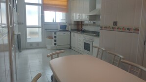 Una cocina con gabinetes blancos, un microondas, una estufa y una mesa de comedor con sillas.