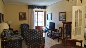 Una sala de estar con sofá, sillones, televisor y una mesa de comedor.