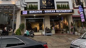 A multi-story building with a sign for 'Bukchon - Korean Restaurant' on the ground floor. - Bukchon Da Lat Hotel (Xuan Huong - Da Lat)