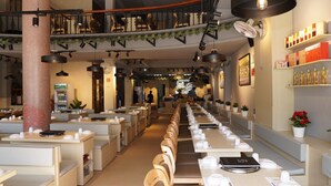 Un restaurant doté de longues tables communes, de petits espaces individuels et d’un passage central.