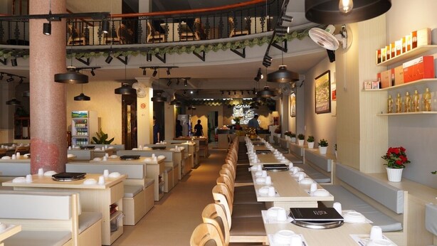 A restaurant with long communal tables, individual booths, and a central walkway. - Bukchon Da Lat Hotel (Xuan Huong - Da Lat)