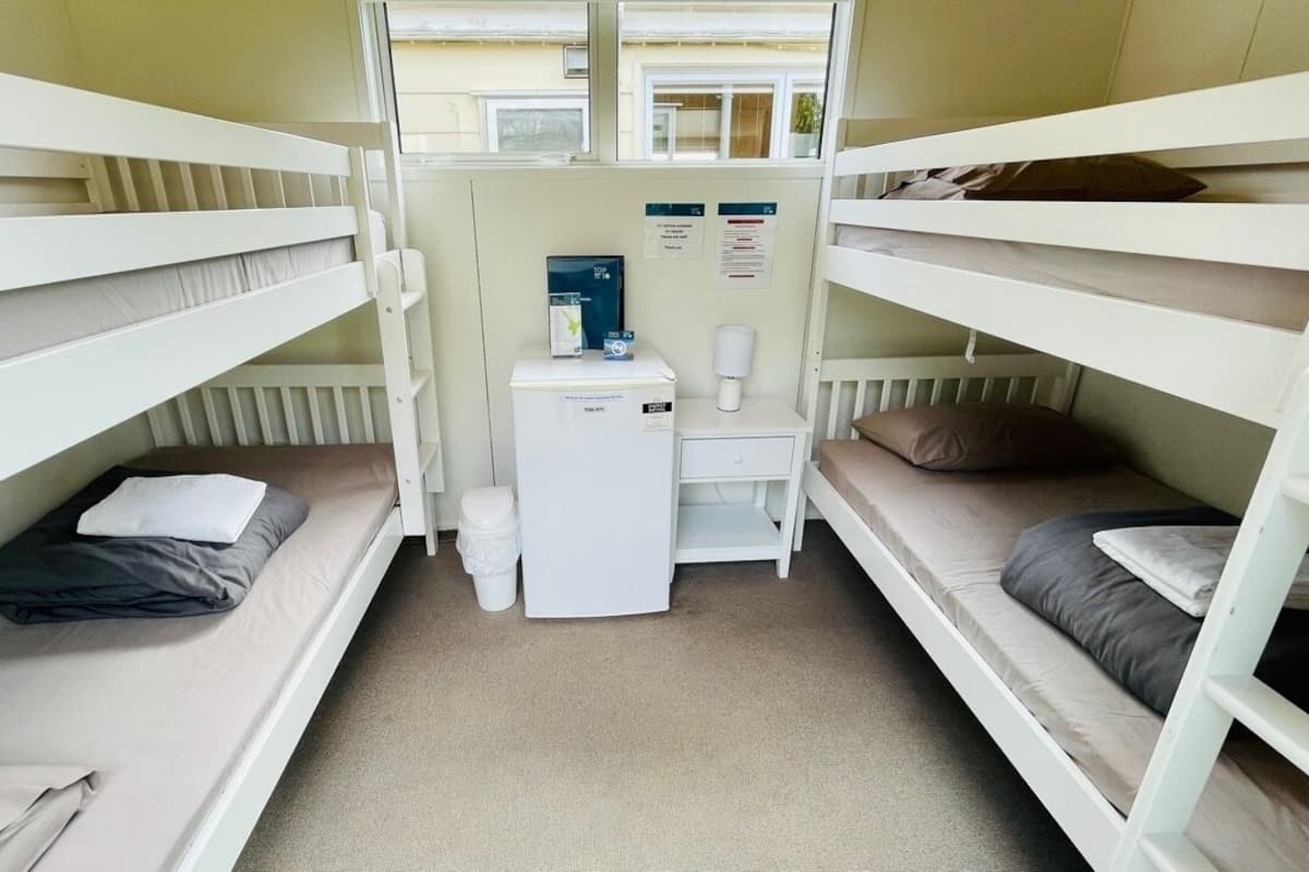 A bunk room with two beds, a small desk, and a radiator.