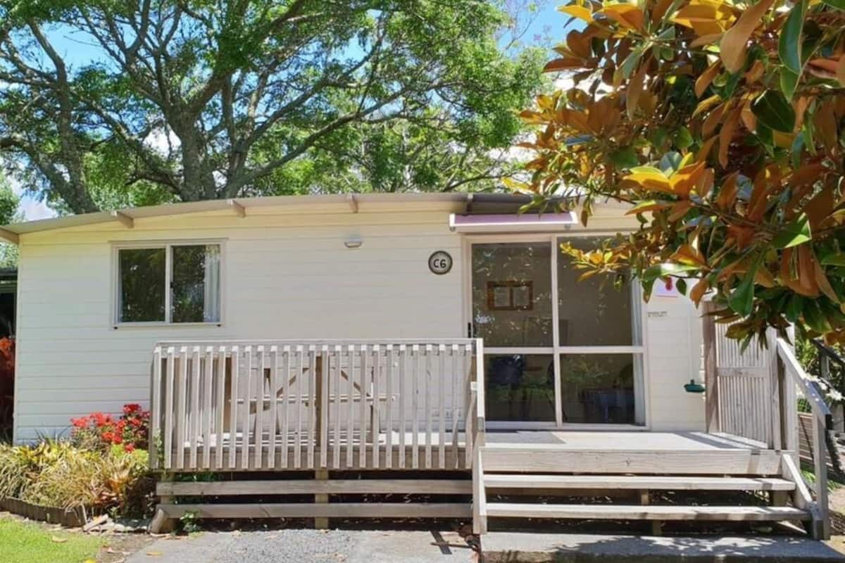 A single-story mobile home with a front porch, a small deck, and a window.