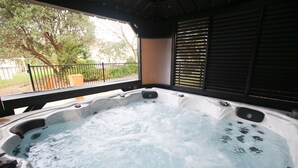 A hot tub with a view of a tree and a fence. - Orere Point TOP 10 Holiday Park (Orere Point)