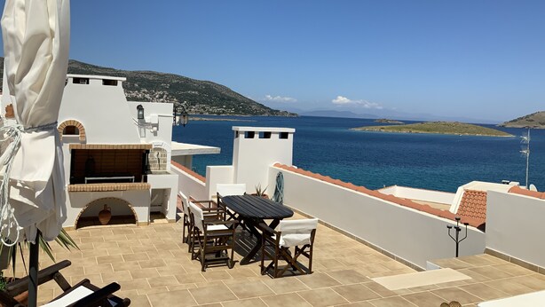 A terrace with a table and chairs, a barbecue area, and a view of the sea and hills. - Baywatch Appartment close to the Airport at Porto Rafti 30 meters from the sea (Porto Rafti)