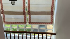 A staircase with a wooden handrail leading to a landing with a view of greenery outside. - Baywatch Appartment close to the Airport at Porto Rafti 30 meters from the sea (Porto Rafti)
