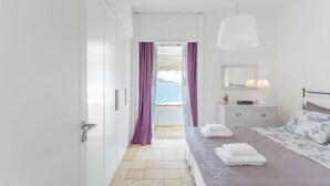 A modern bedroom with a bed, bedside table, and a view of the sea. - Baywatch Appartment close to the Airport at Porto Rafti 30 meters from the sea (Porto Rafti)