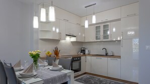 A modern kitchen with white cabinets, a dining table set for four, and pendant lighting.