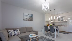 A modern living room with a sofa, coffee table, and a dining area with chairs and a table.