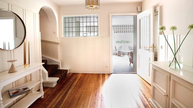 A hallway with wooden flooring, white walls, a staircase, and a door leading to another room. - Lohmann's apartment (Garstedt)