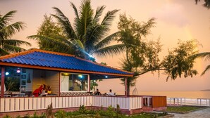 A coastal building with a blue roof, surrounded by palm trees and overlooking the sea. - Scarlet Sails Resort (Koh Rong)