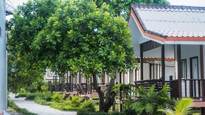 A building with a covered porch and a large tree in front. - Scarlet Sails Resort (Koh Rong)
